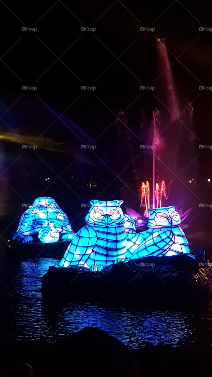 Brilliant blue animals make their way in front of a red and pink fountain on the waters of Discovery River during Rivers of Light at Animal Kingdom at the Walt Disney World Resort in Orlando, Florida.