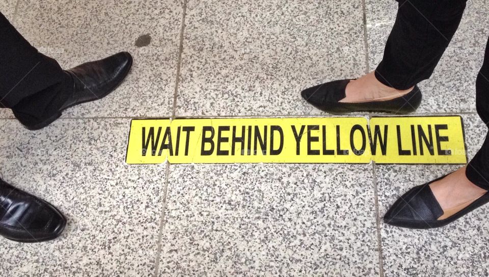 Stand behind yellow line sign