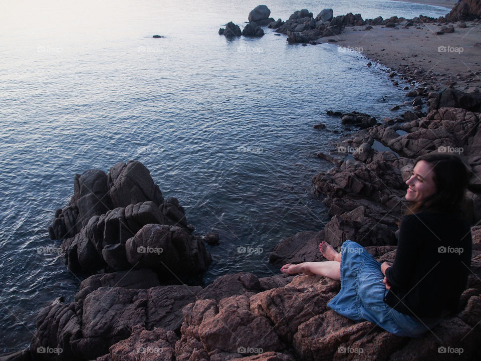 Woman sitting on rock at beach