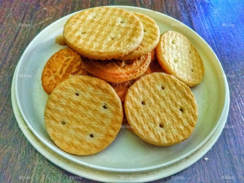 Pile of biscuits on white plate on wooden table