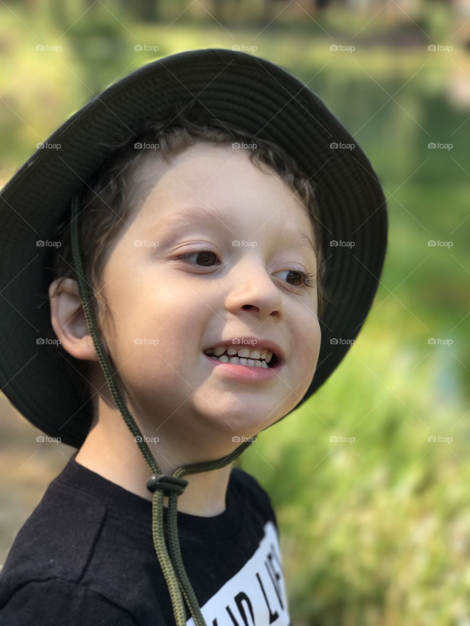 An adorable little boy wearing a hat out hiking in the woods of Central Oregon on a sunny summer day. 