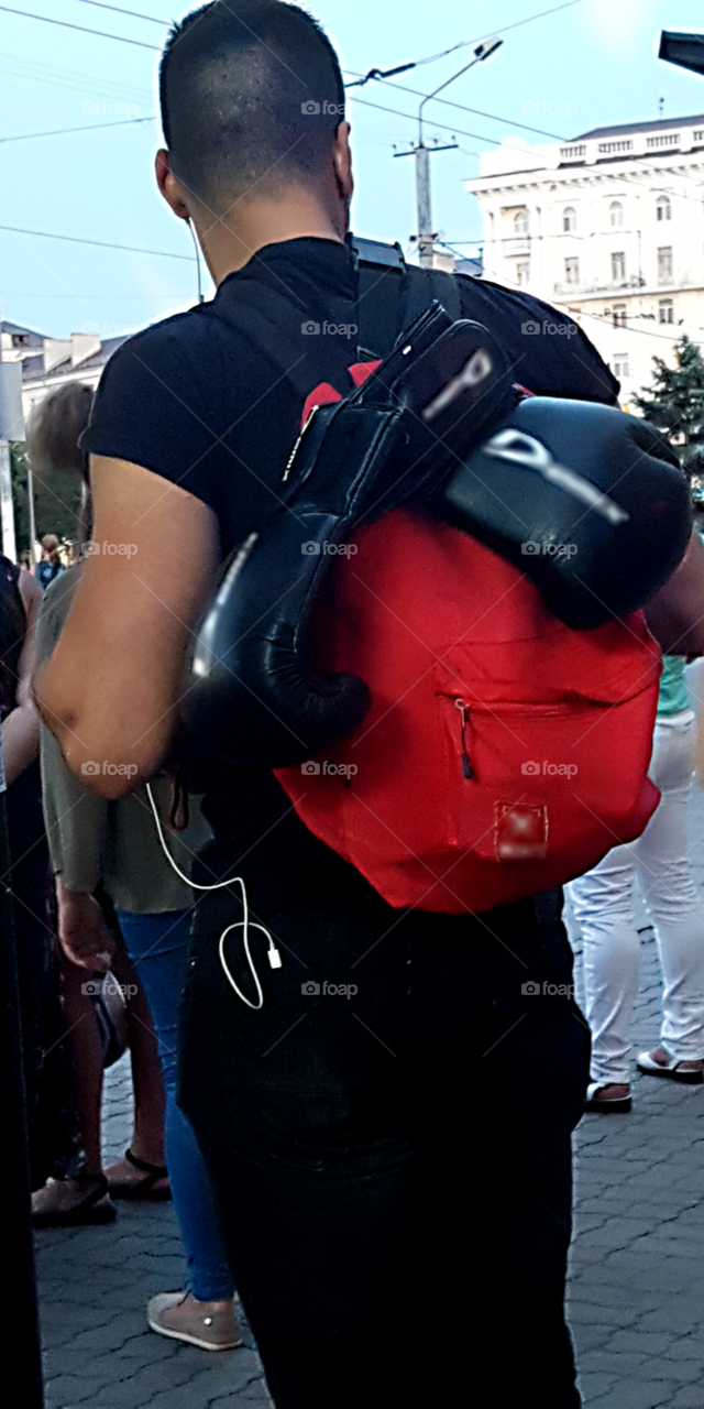 A man sports figure with a red backpack and boxing gloves.Young man with headphones