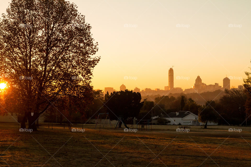 Sunrise over a local park with the Sandton skyline in the background. Sandton and Nelson Mandela square are frequently visited by tourists. Sandton, Johannesburg, South Africa