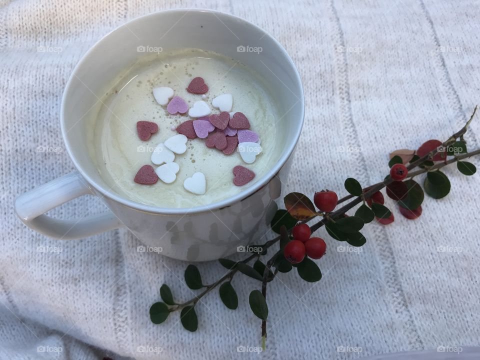 White cup of white-hot chocolate with little sugary hearts on the top.