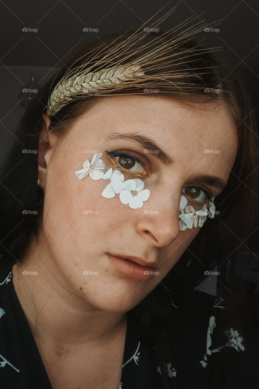 Portrait of a girl with white petals and a yellow ear of corn