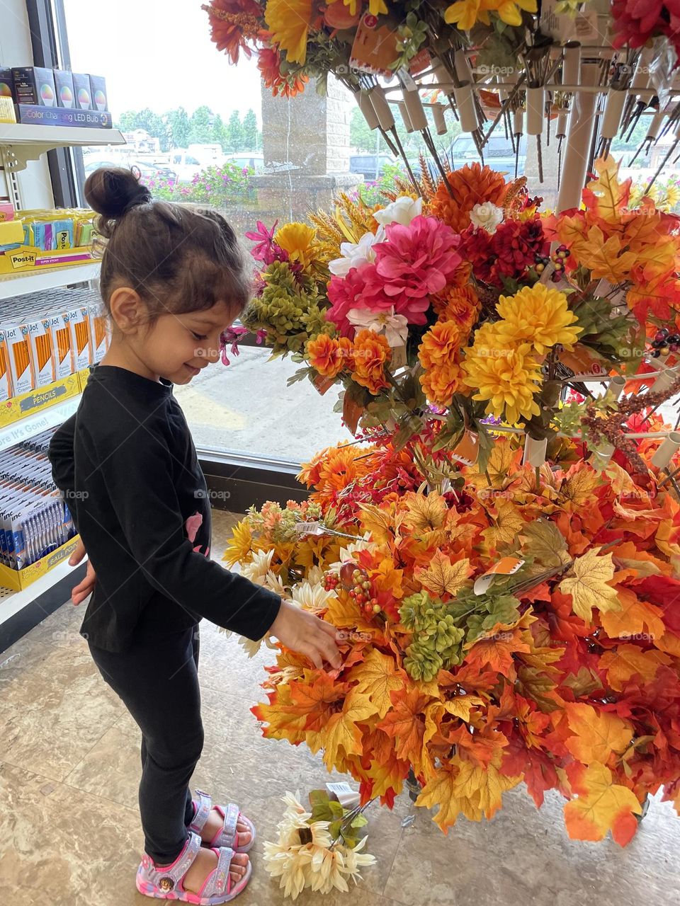 Little girl smell the flowers at Dollar Tree, toddler looks at fake flowers in the Dollar Store, buying fake flowers at Dollar Tree, toddler excited about fake flowers 