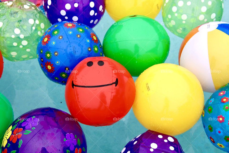 Bright Colorful balls with smiley face on one red ball in pool