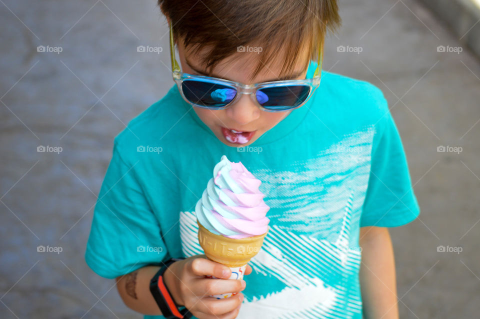 Close-up of a young boy eating an ice cream cone outdoors in the summer