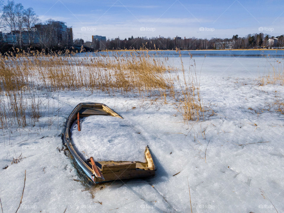 Abandoned rowing boat full of ice and snow in the middle of reeds and ice by the Baltic Sea in Espoo, Finland.