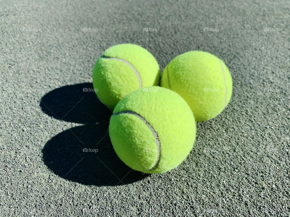 Three tennis balls on clay courts 