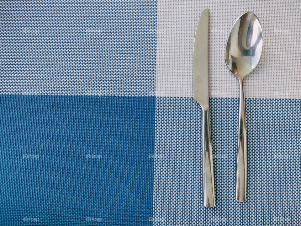 Knives and spoons on plastic mat pads placed on the tableware.