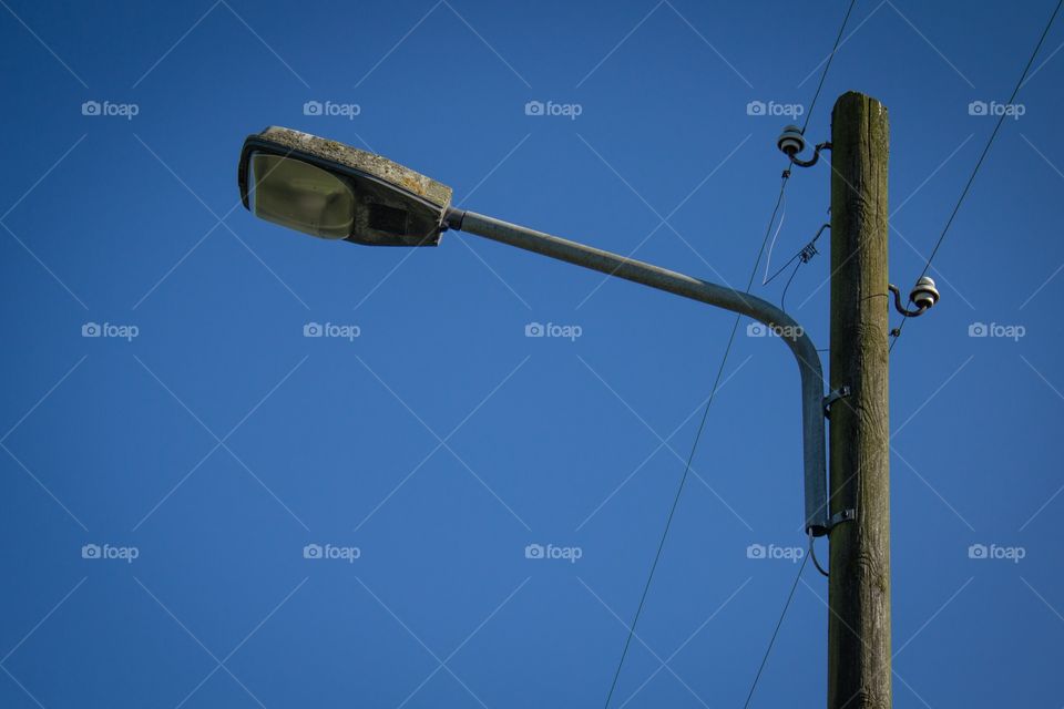 Street light with wooden pole against blue sky
