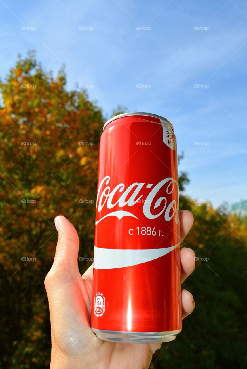 coca cola in hand blue sky background, drinking coca cola outdoor