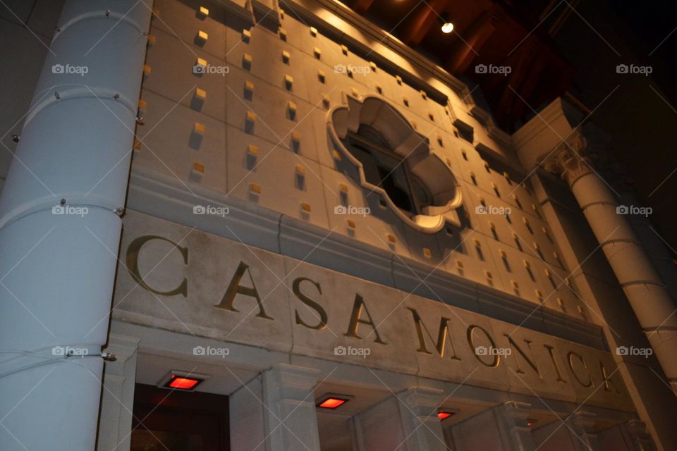 A closeup view of an old hotel building with a large ornate window in a Mediterranean style at nighttime