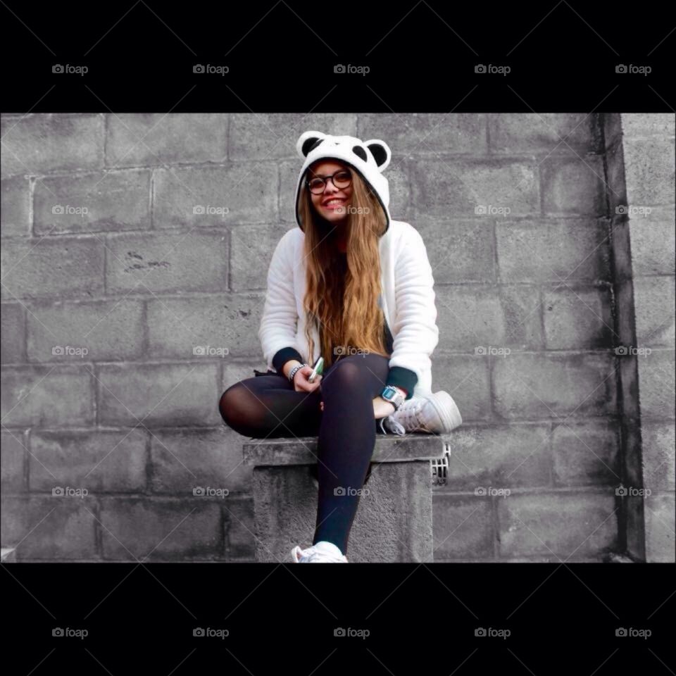 Girl sitting on concrete block of wall