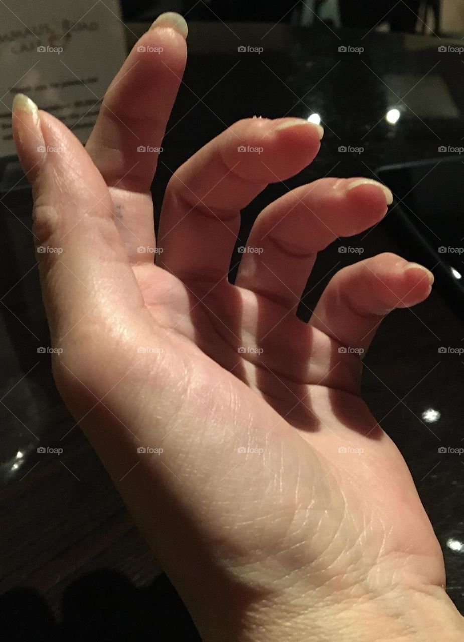 Finger shadows fall on the palm of a graceful and elegant slightly curved hand. 