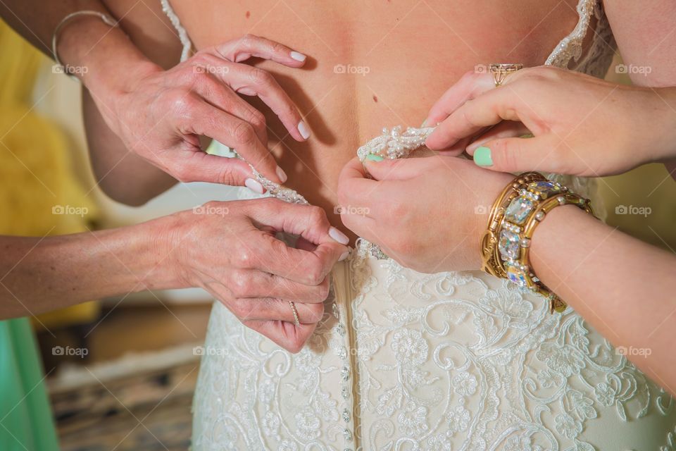 Bridesmaid helping bride with wedding dress