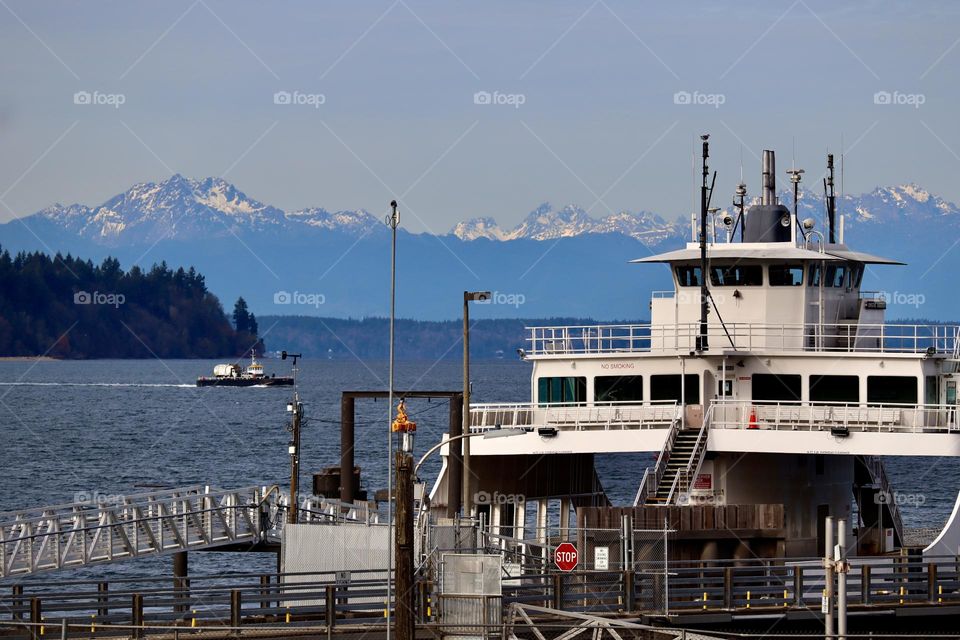 A  ferry docks to collect commuters to Anderson Island near Steilacoom, Washington on a clear December afternoon. Olympic Mountains show snow capped tops in background