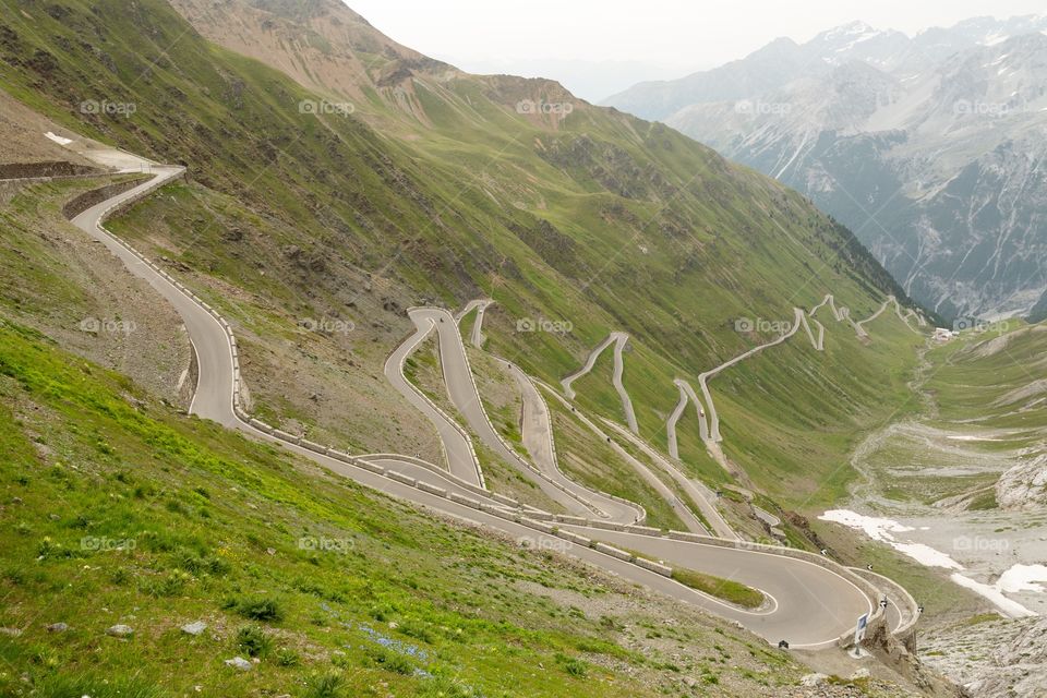 Curvy road on mountains. Very famous and curvy road on mountains. Several hairpins. Stelvio pass, Italy. Green hills. Snow peaks