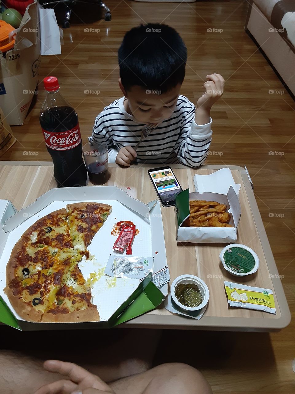 eating dinner while busy of his fone with coca cola beside him to drink anytime