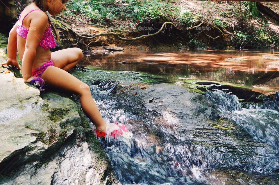 Side view of a girl sitting on rock