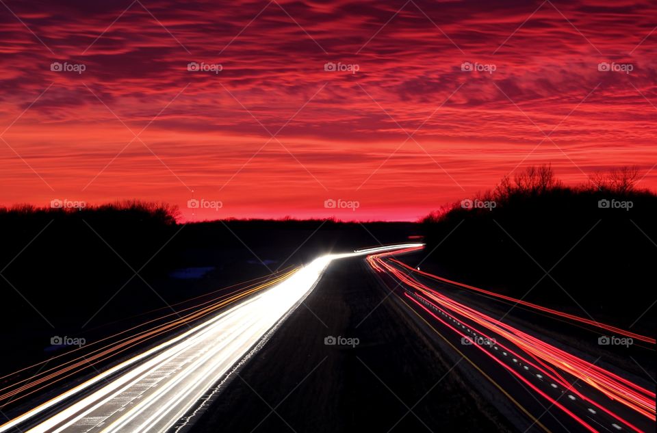 Into The Sun: Light trails on the highway moving swiftly into a beautiful sunset. 