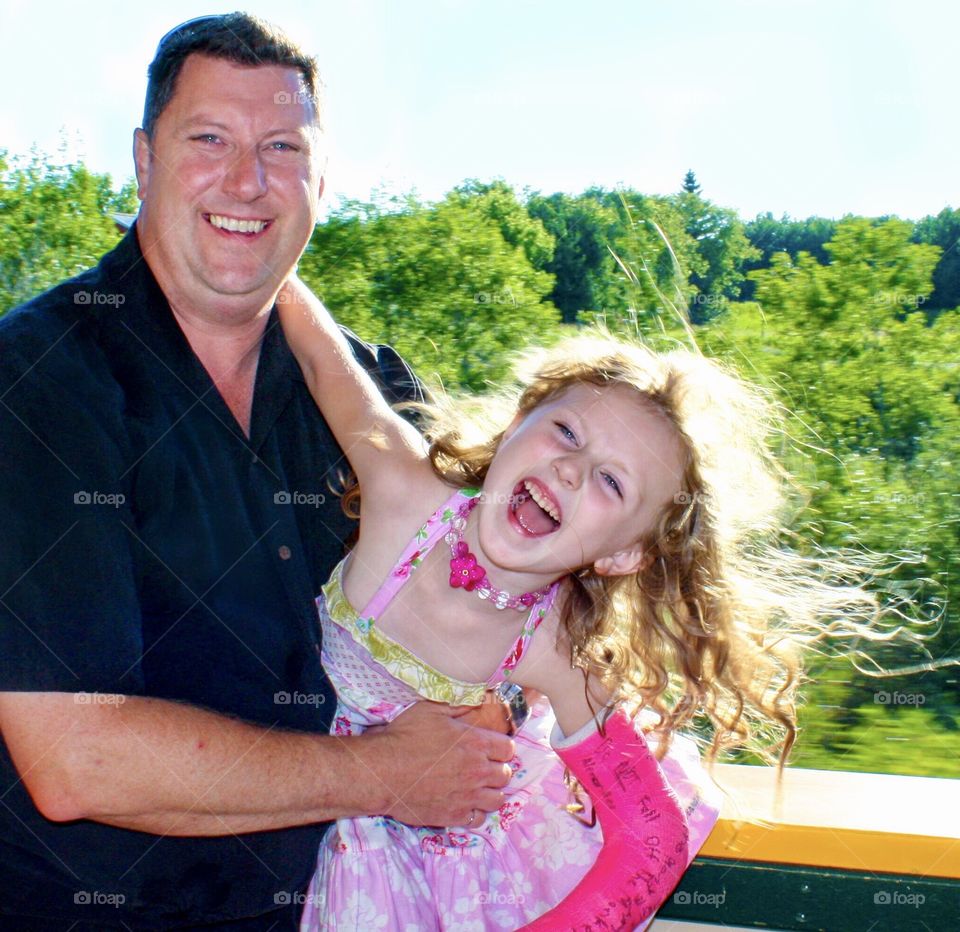 Fun dad and daughter laughing during an open-car train ride