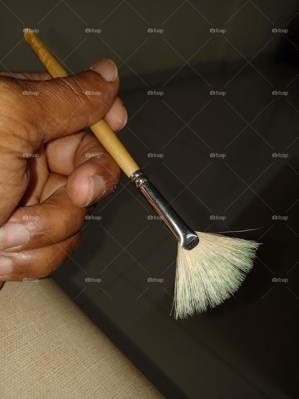 Young man holding panting bresh for doing sum pant art closeup photo in night time enjoying panting part time hobbies