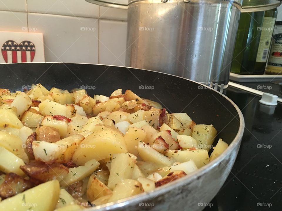 Home fried diced herbed new potatoes in fry pan 