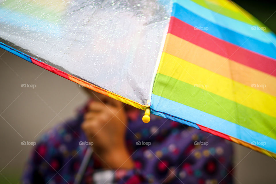 Child is holding wet colourful umbrella