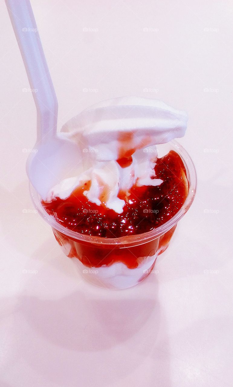 Delicious milk creamy ice cream with strawberry sweet gem in transparent cup
agains white backround
