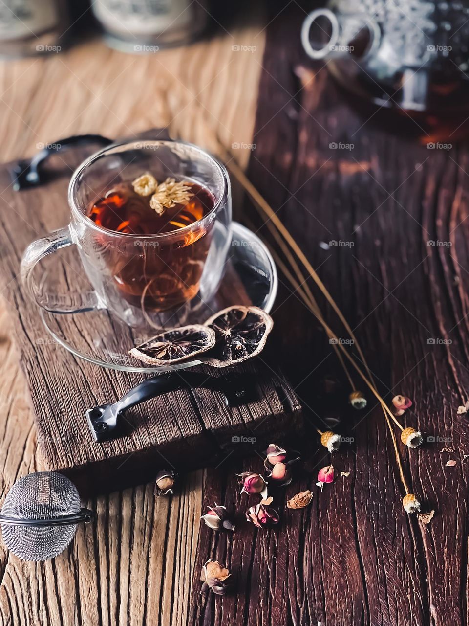 Hot flower tea in a clear cup and saucer on a wooden board