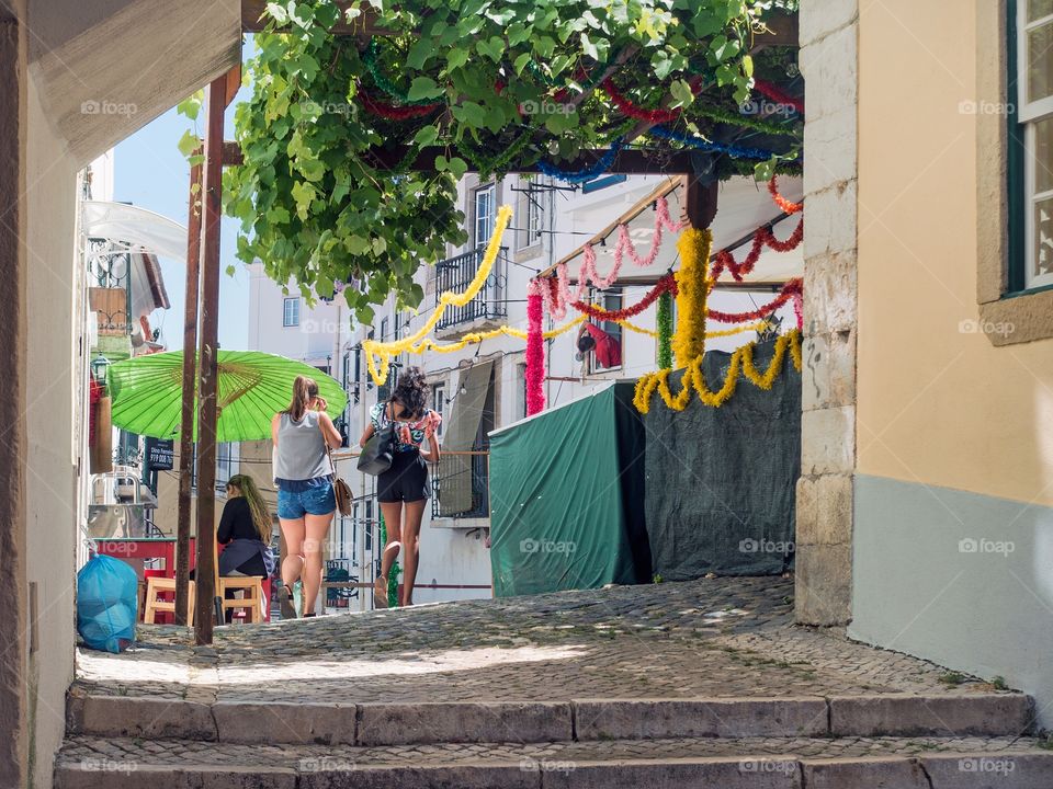 Two young women from behind walking in an alley in Alfama, Lisbon, Portugal