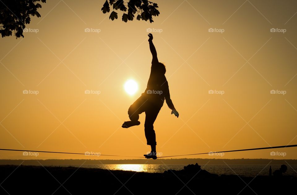 Slack liner in the sunset. A slack liner trying to keep his balance during sunset