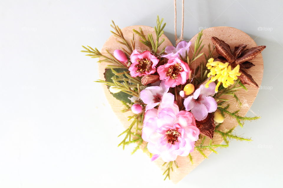 beautiful wooden heart with artificial flower patterns elements hanging on the closet door