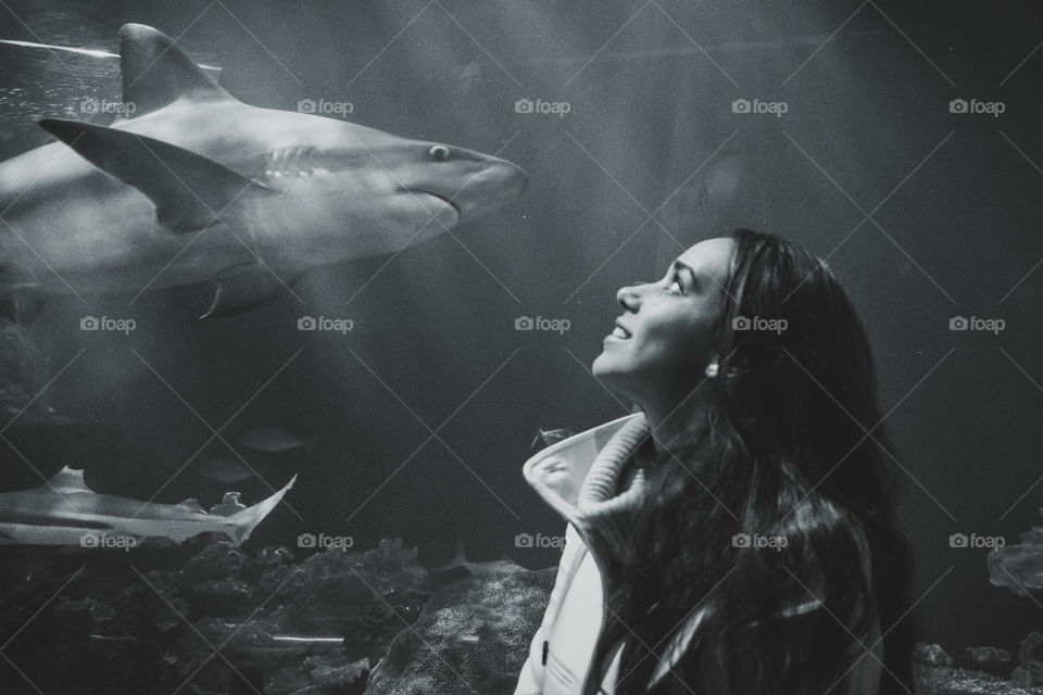 Woman looking at shark in aquarium