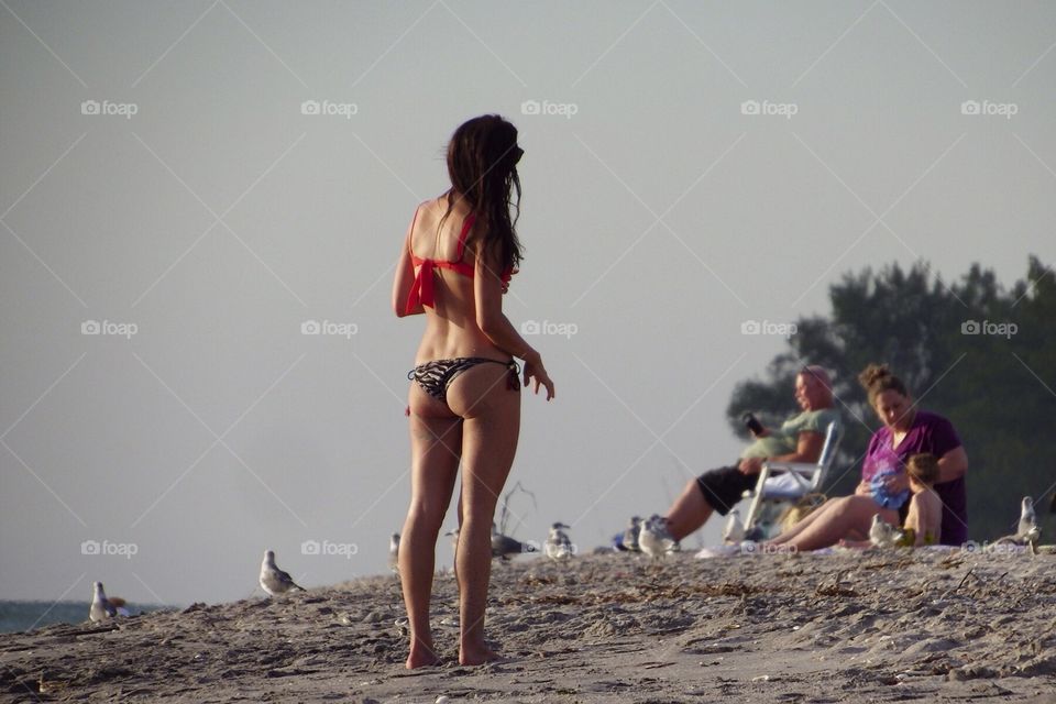 Woman in great shape wearing a t-back bathing suit at the beach.