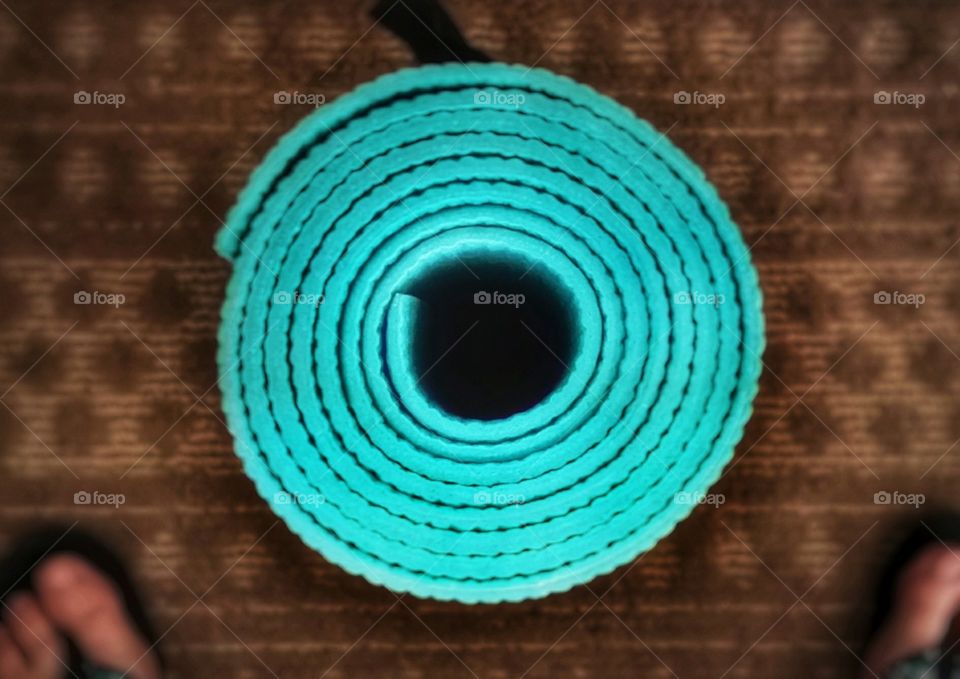 Rolled up yoga mat from above on a brown rug with circles