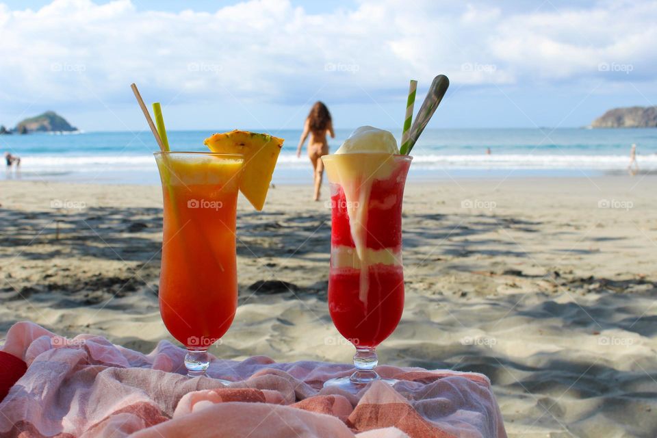 Two cocktails with exotic fruits and ice cream in the shade of a beautiful beach in Costa Rica