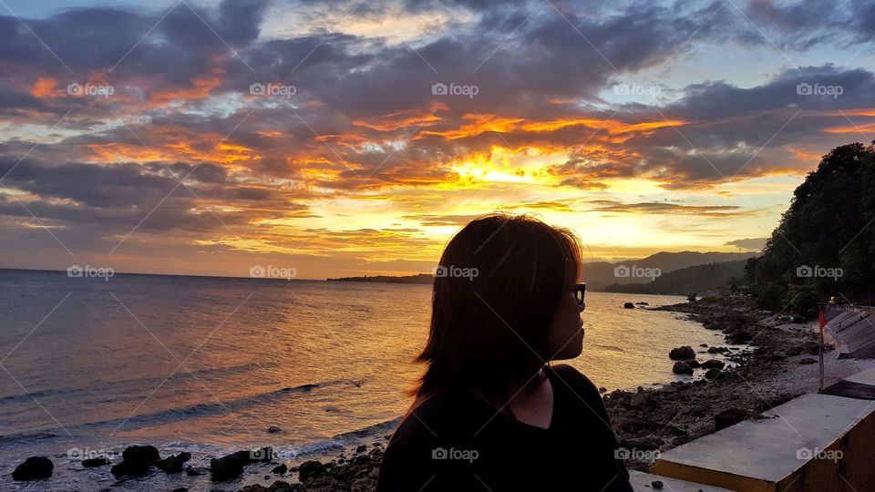 Girl looking at the side with sunset by the beach background