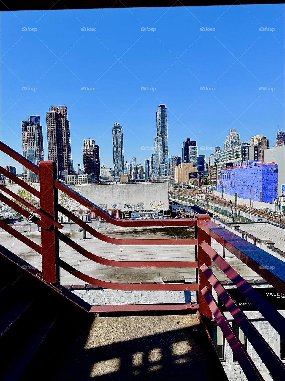 This is the view from the top of the red metal staircase of the “Pulaski Bridge” at “Newtown Creek” in LIC, Queens overlooking the LIRR train tracks, LIC and “Manhattan” on a warm Indian summer afternoon in early November 2023. Hypnotic Productions