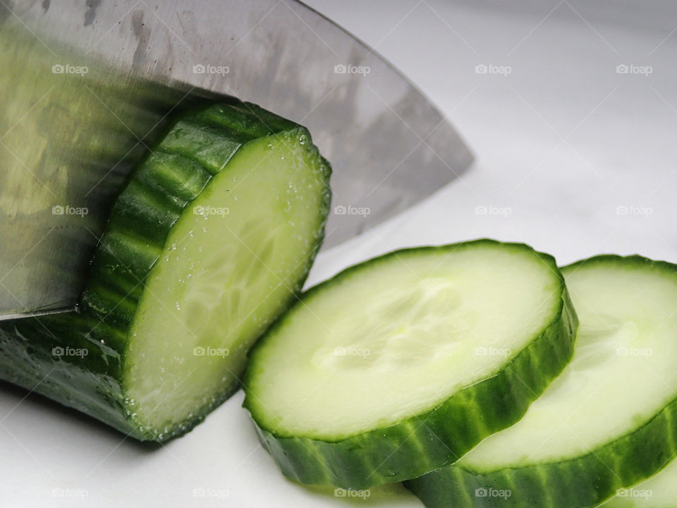 Cucumber being cutted in fresh slices with a sharp metal knife