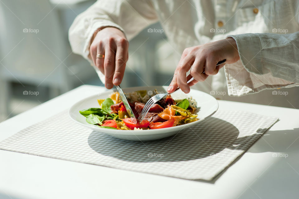 close-up of a young man eating a salad in a light kitchen