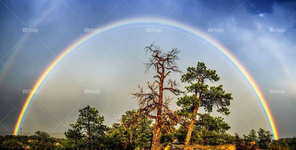 View of double rainbow against stormy clouds