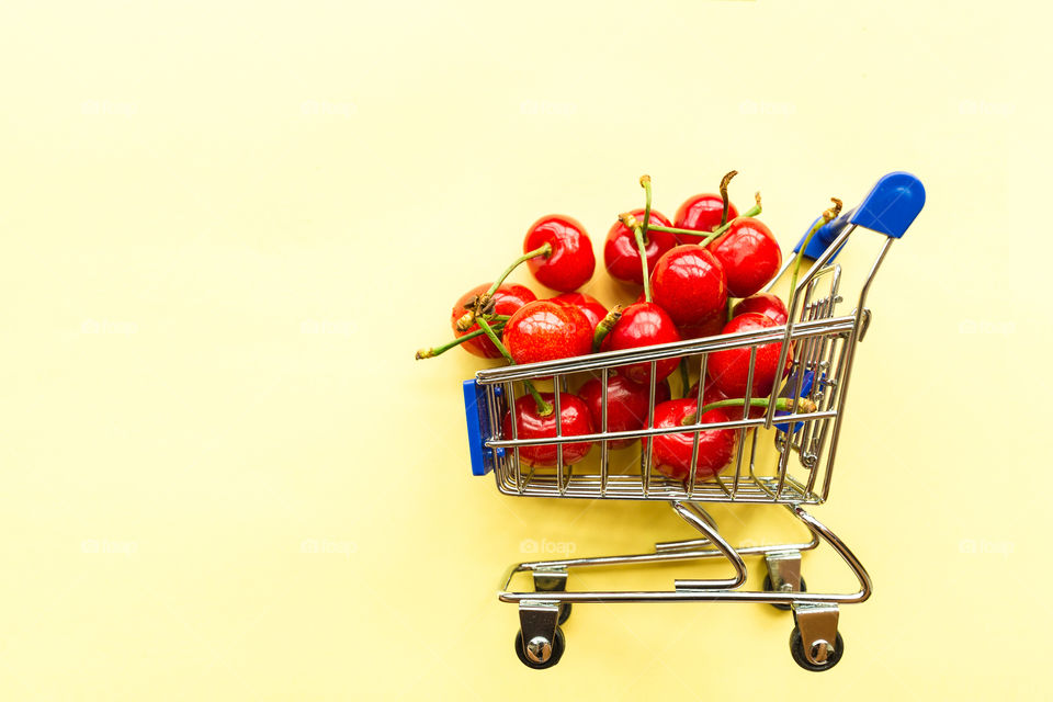 Fresh cherries lying in mini grocery cart