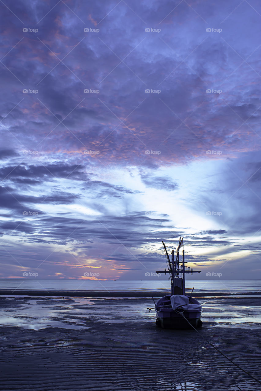 The morning sun light in the sea and the boat on the beach.