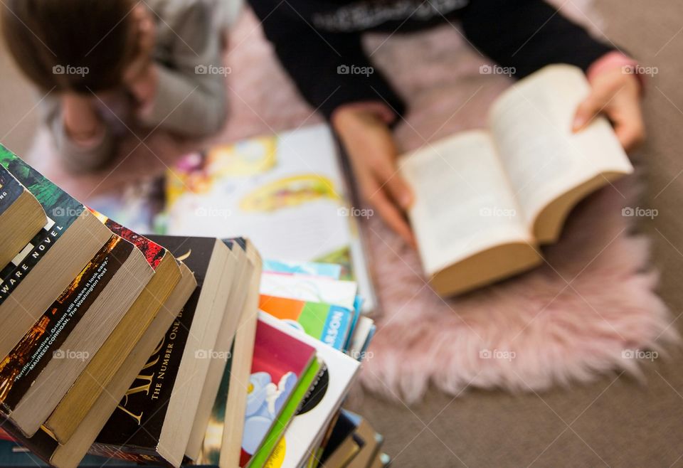 I love to read! Image of woman and girl reading together with a stack of books close by