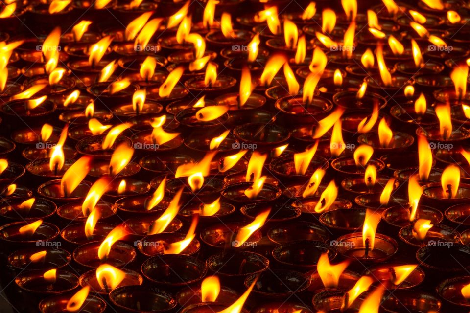 Photo full of burning candles. Frame filled with burning candles. Yellow orange flame. Cup candles