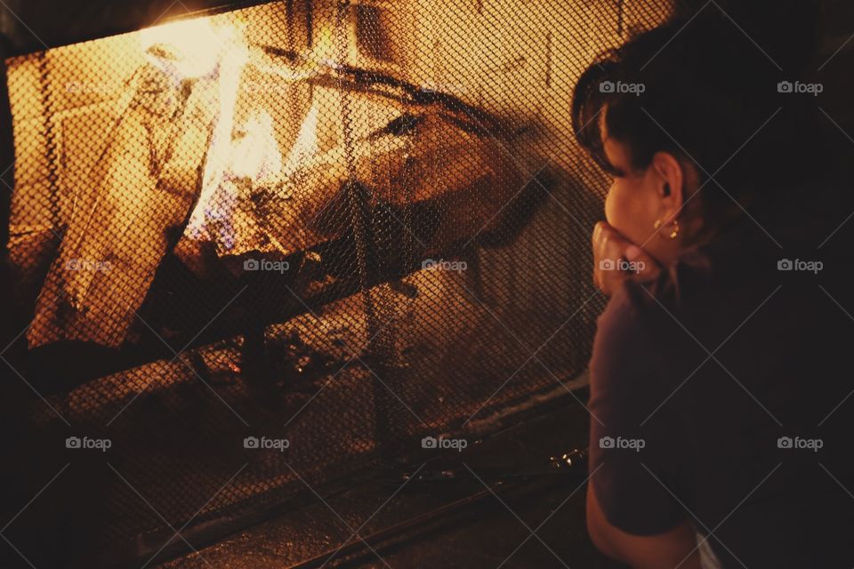 Girl Sitting by fireplace, woman sitting at fireside, watching a fire, flames in a fireplace, girl warming up, first signs of winter, staying inside from the cold, fire logs and fire place