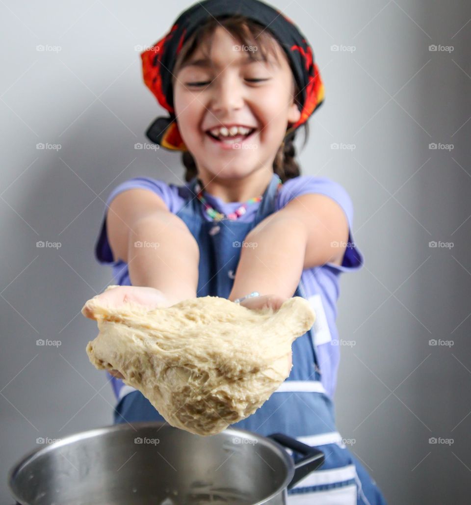 Happy cute girl with a bread dough